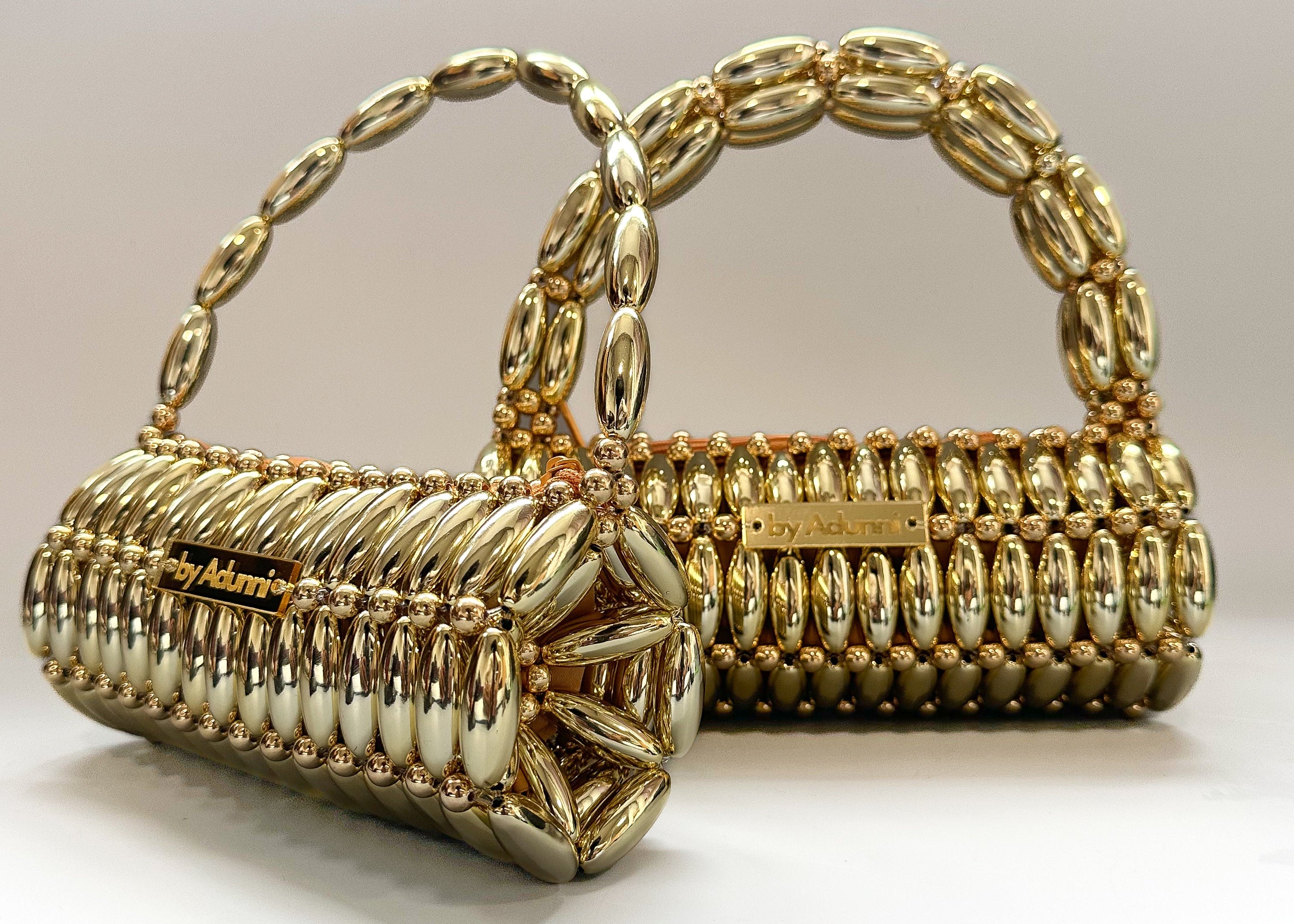 Gold handbag with pearl detailing on a white background