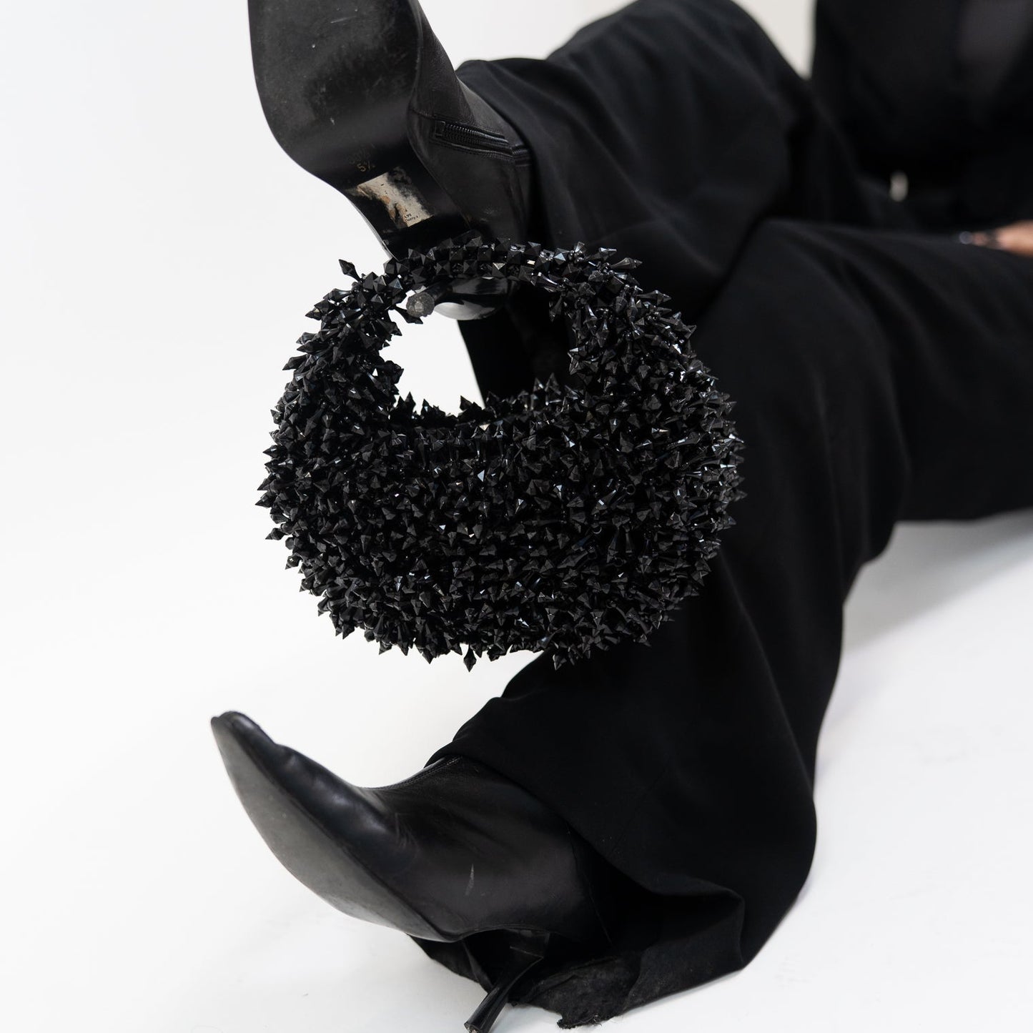 Black high-heeled shoes with decorative black circular design on a white background