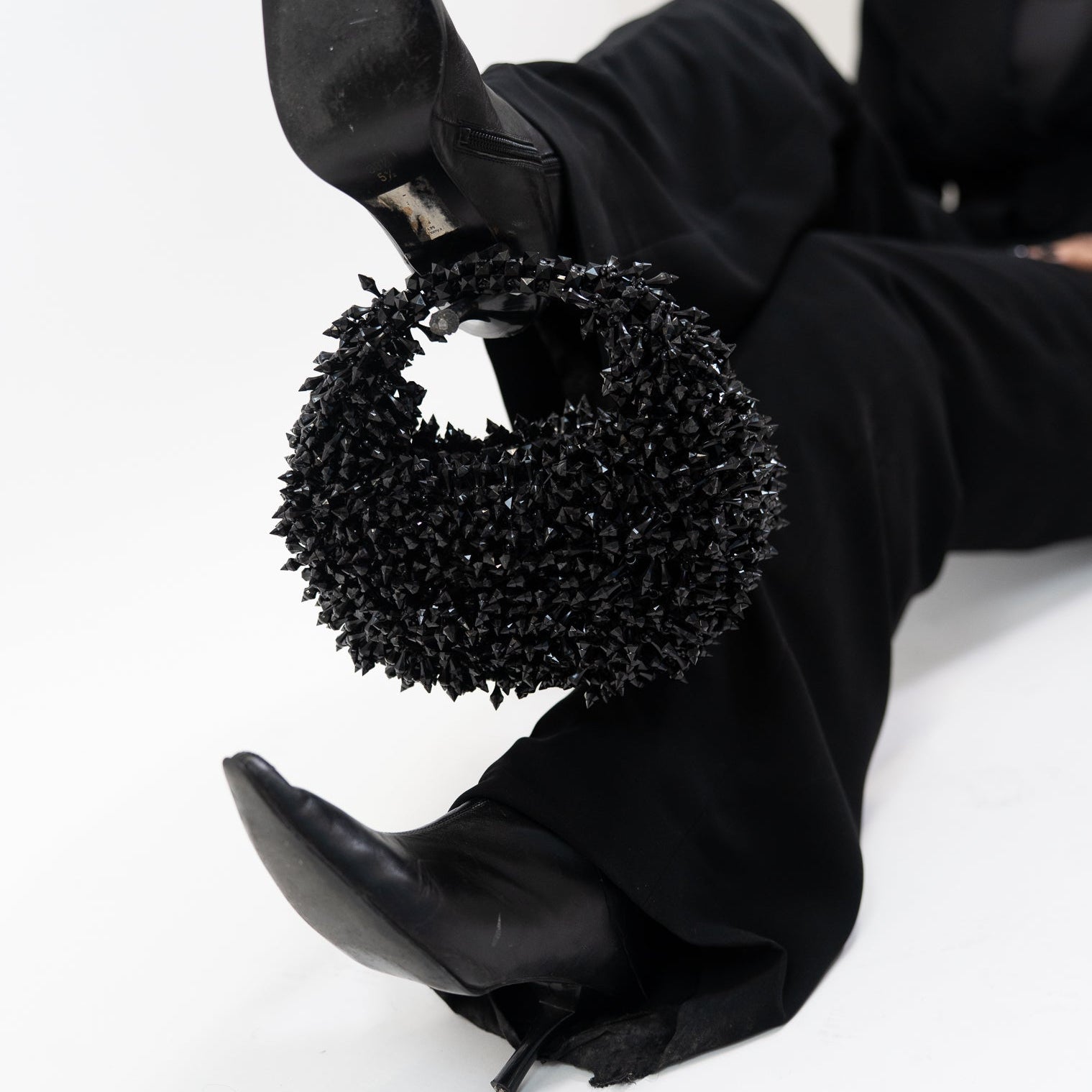 Black high-heeled shoes with decorative black circular design on a white background