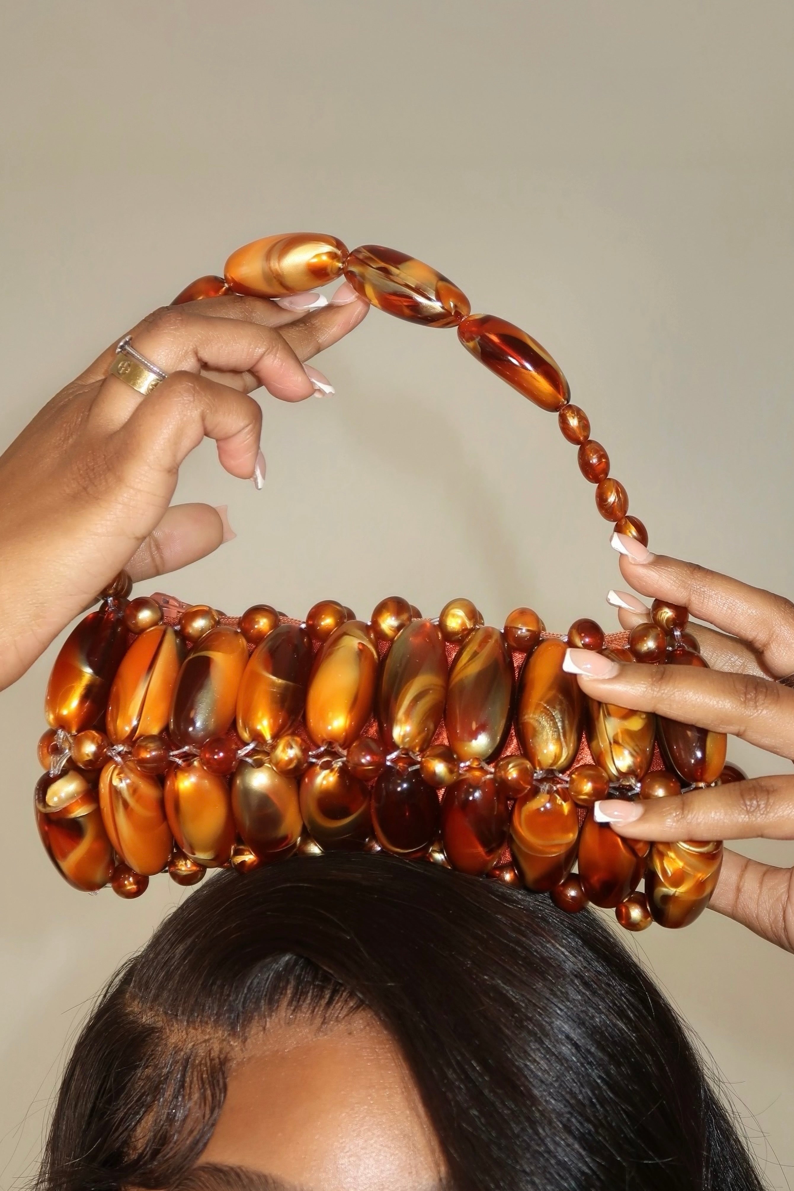 Model holding madagascar beaded bag above head