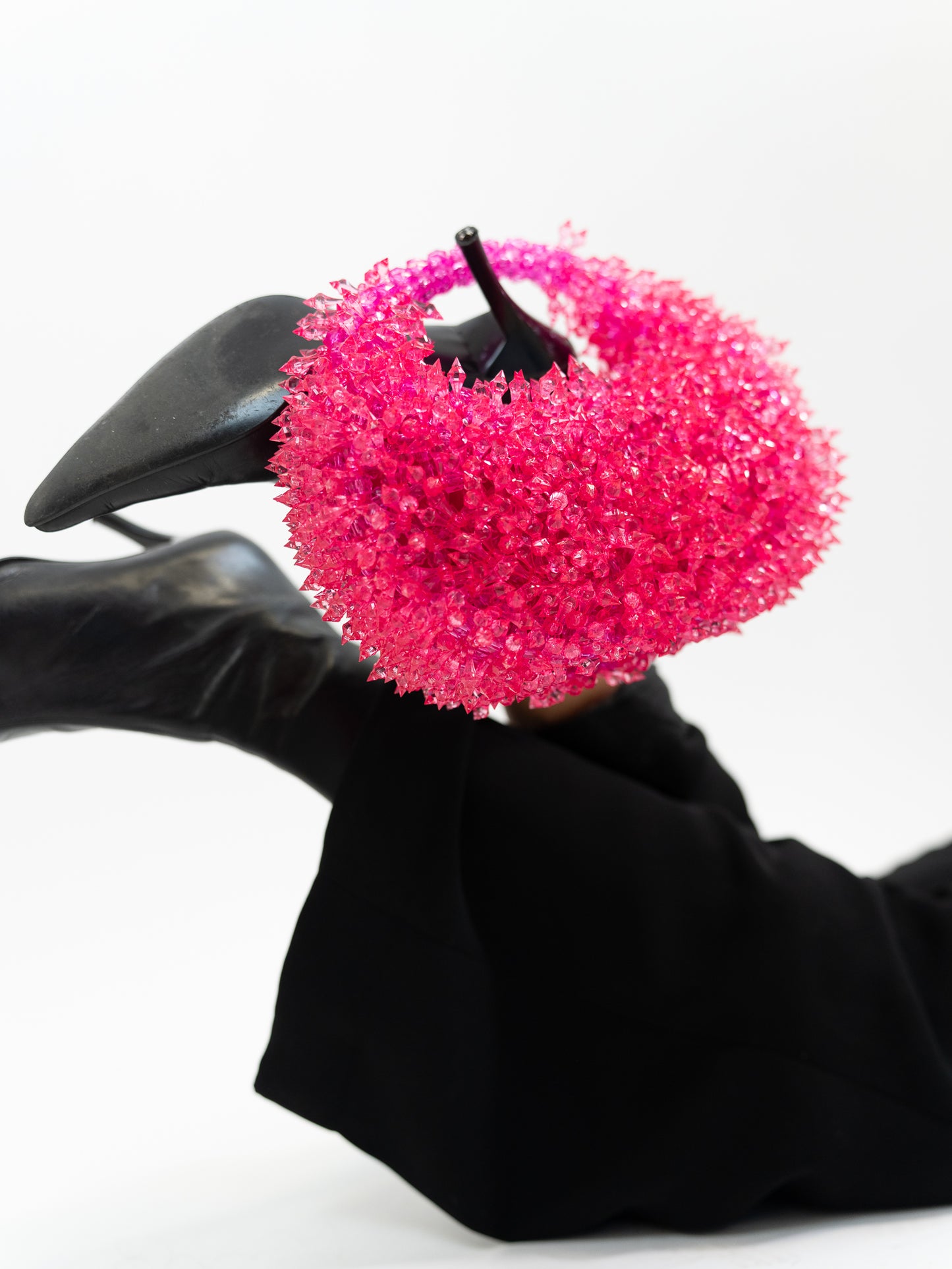 Model holding hot pinked spiked handbag on heeled boot