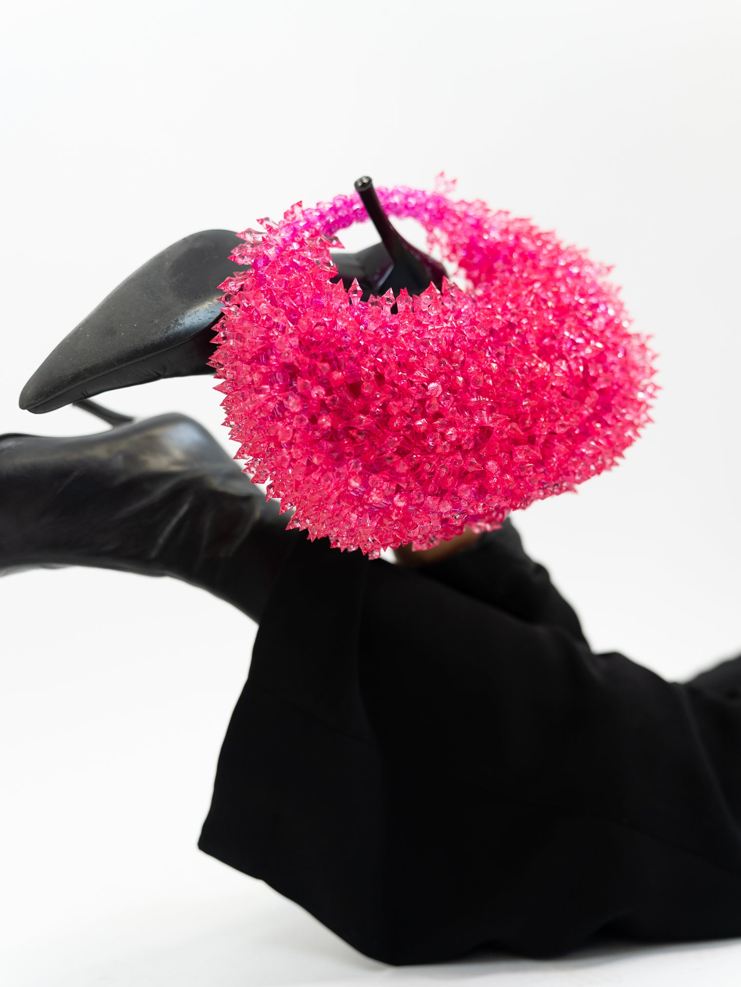 Model holding hot pinked spiked handbag on heeled boot