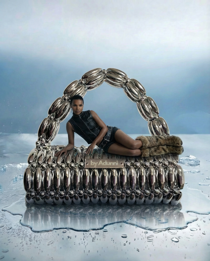 Large silver handbag with a person sitting inside on a reflective surface