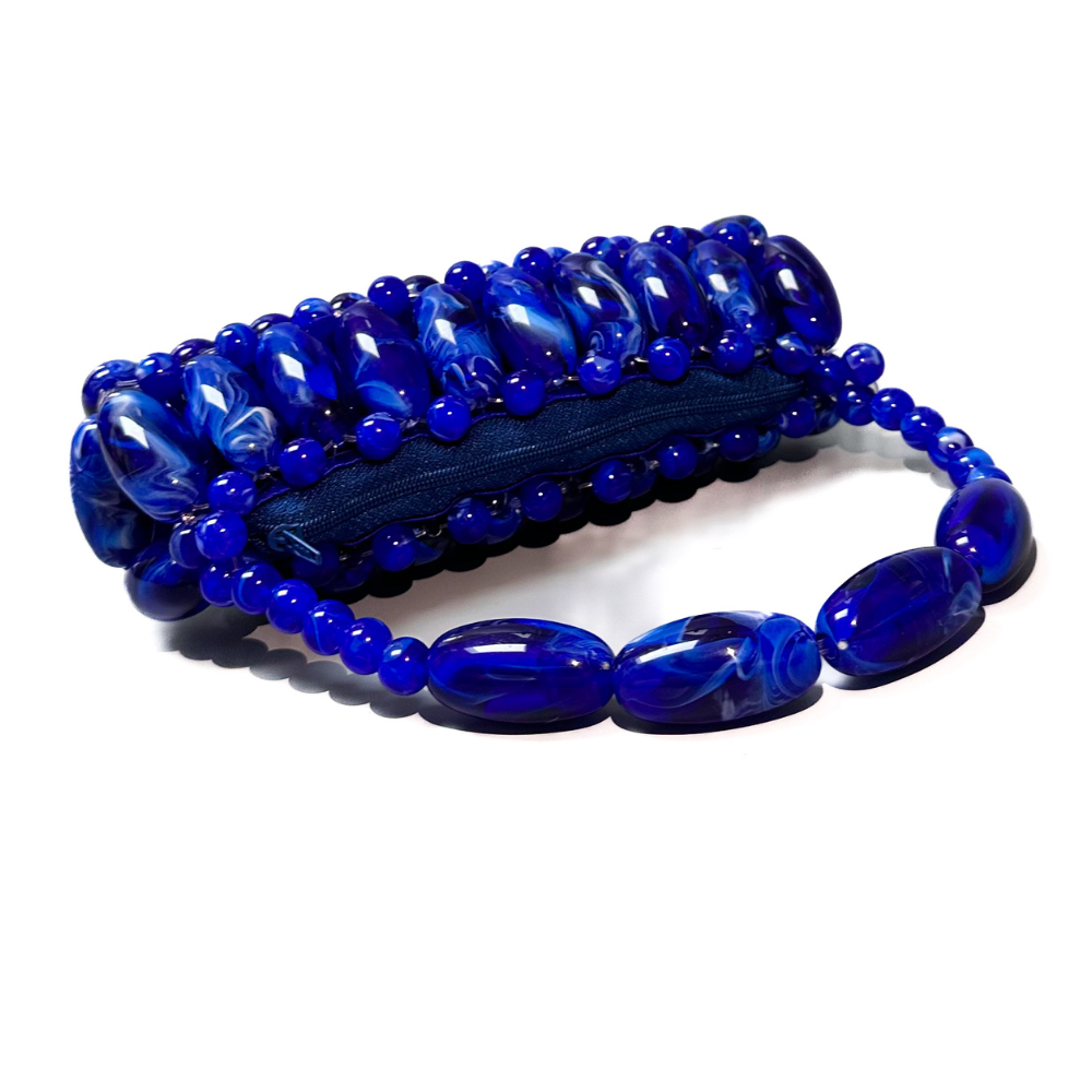 Close up of handmade beaded bag in electric blue, dark blue, light white marble swirled tones laid flat to display the blue zip pouch