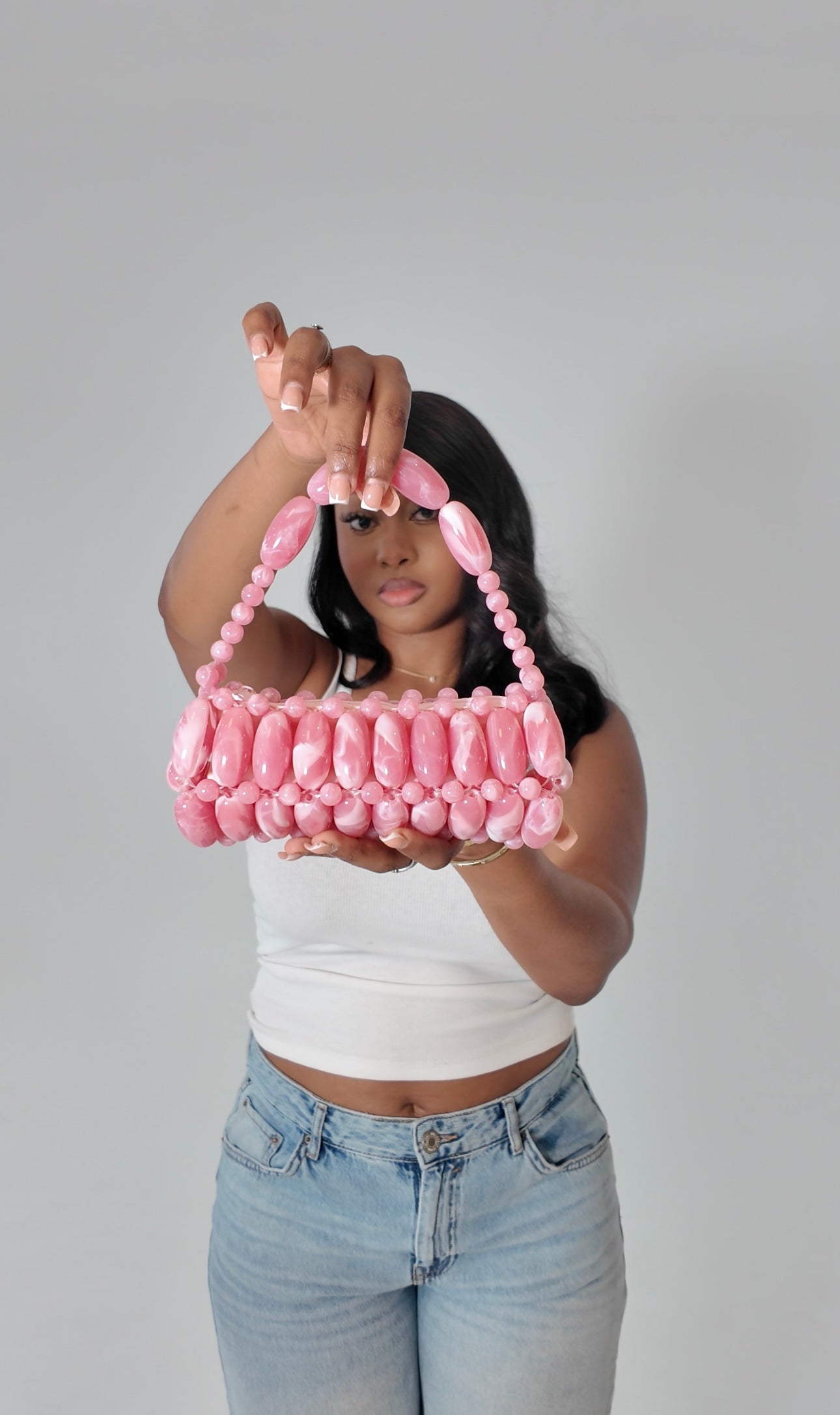 Model holding fuchsia pink beaded bag towards the camera