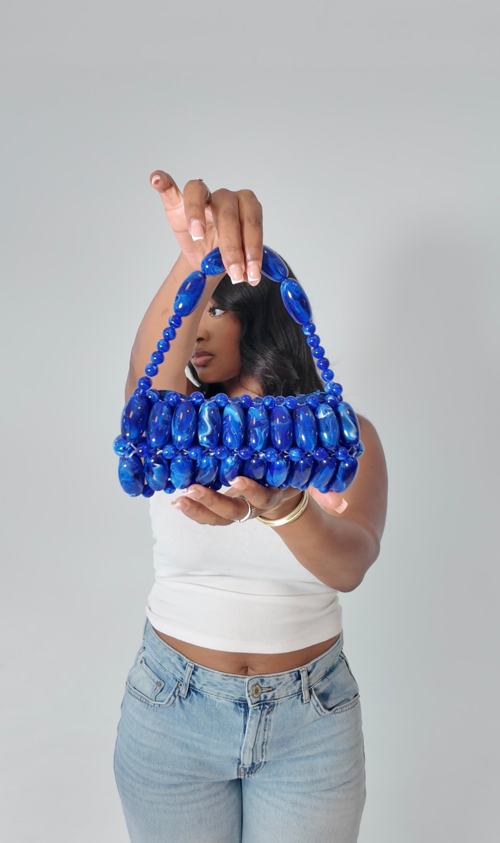 Model holding handmade beaded bag in electric blue, dark blue, light white marble swirled tones