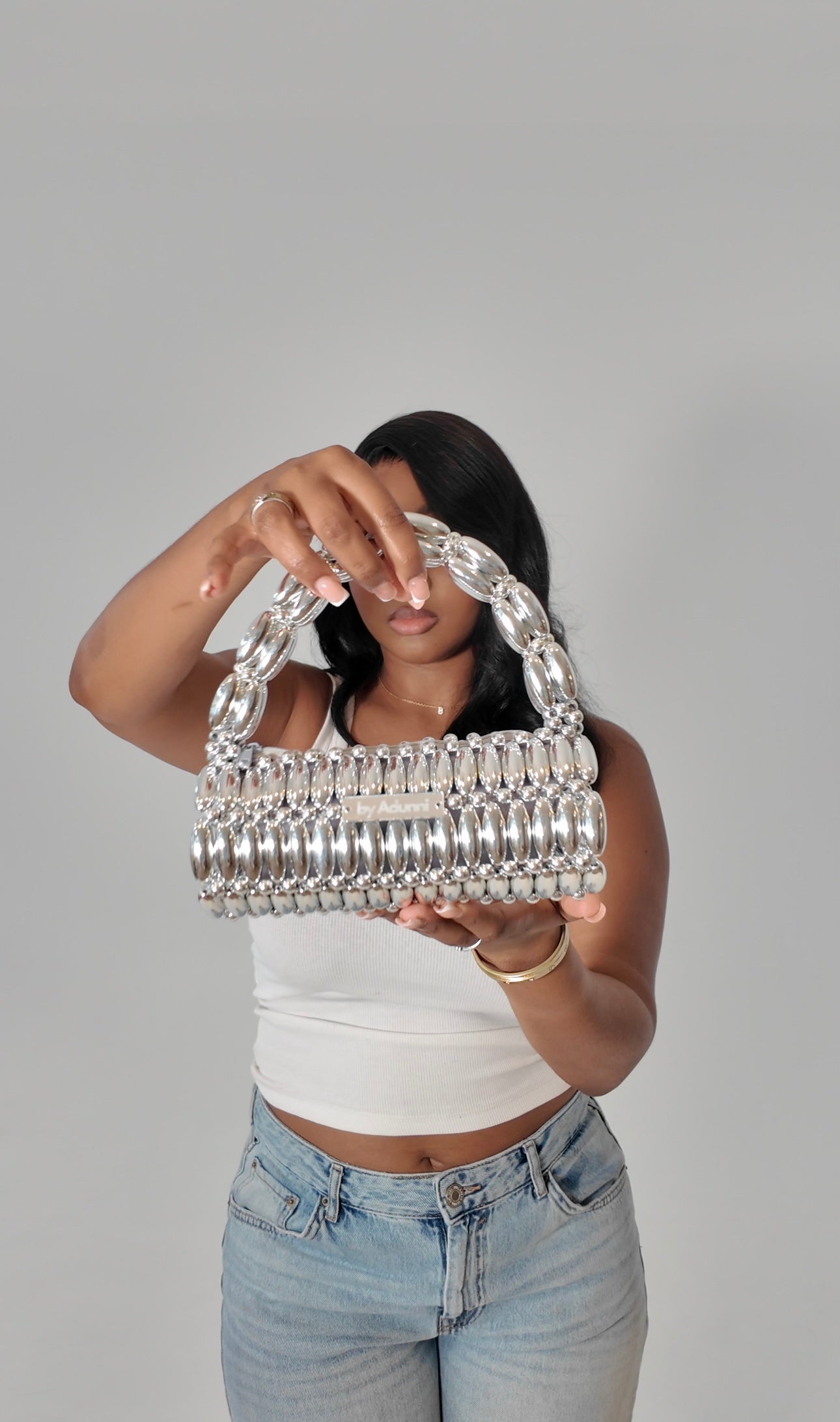 Model holding silver/platinum beaded bag to the camera