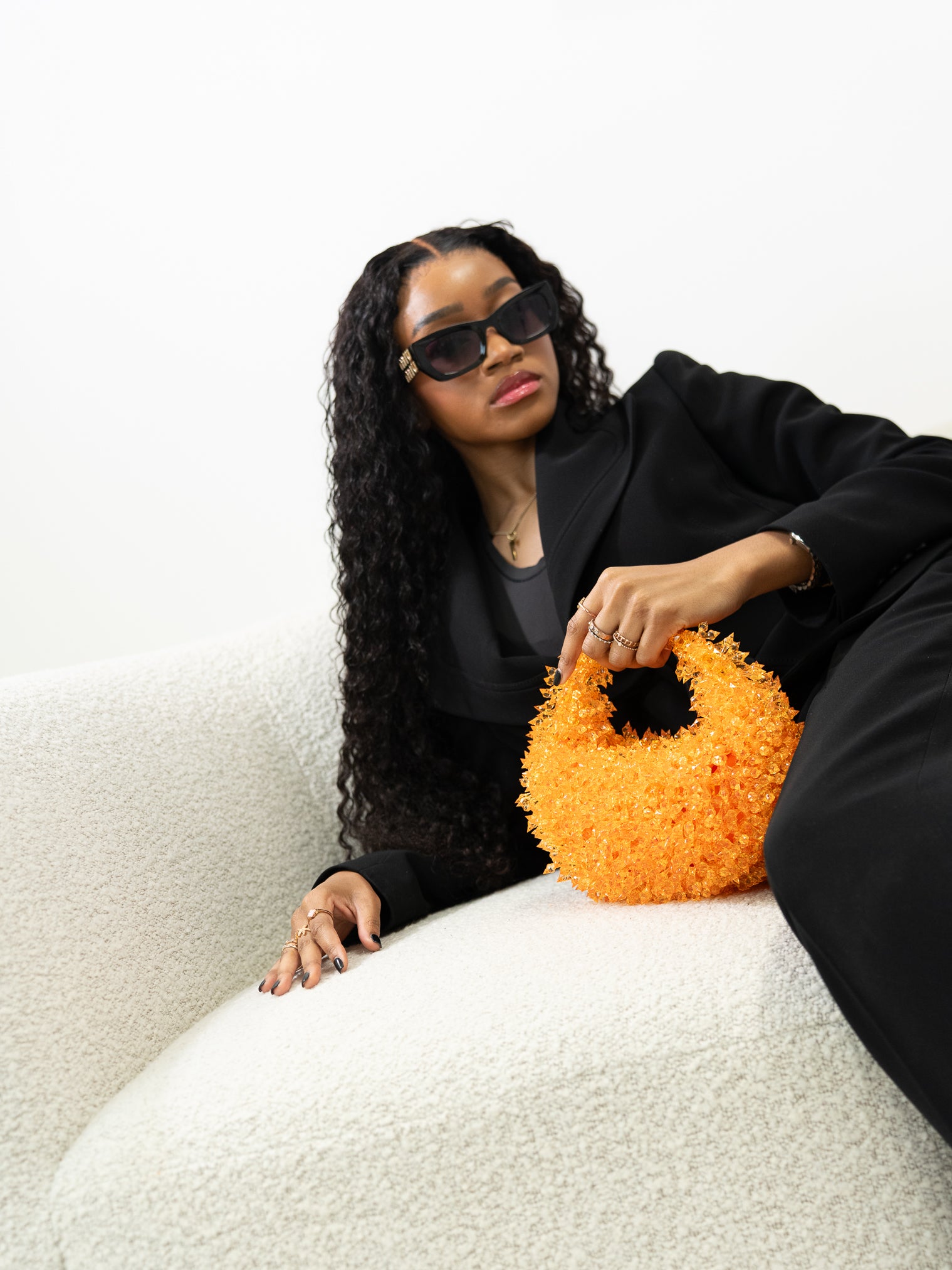 Woman holding an orange textured handbag on a white background