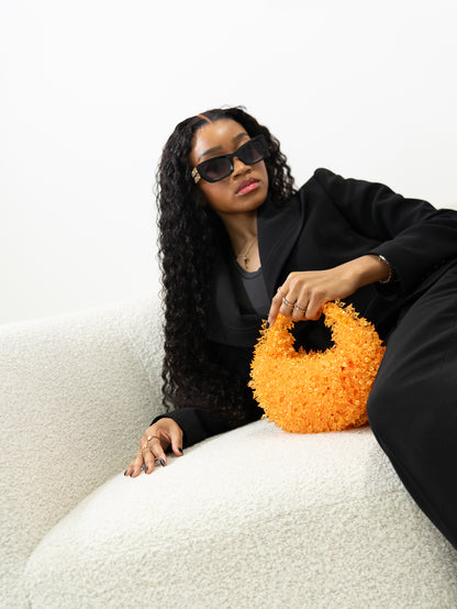 Woman holding an orange textured handbag on a white background