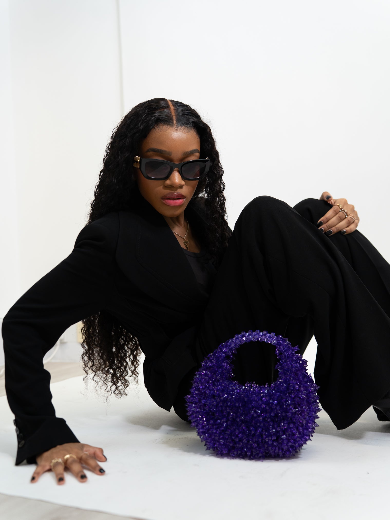 Woman sitting on the floor with a purple handbag in front of her