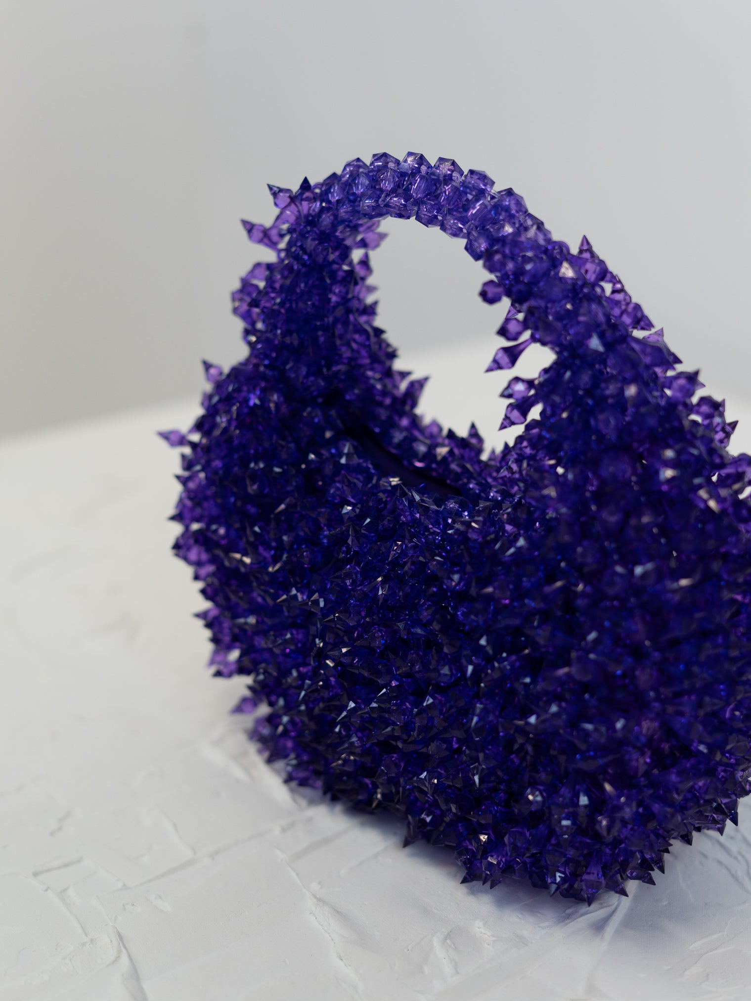 Purple crystal cluster on a textured white surface