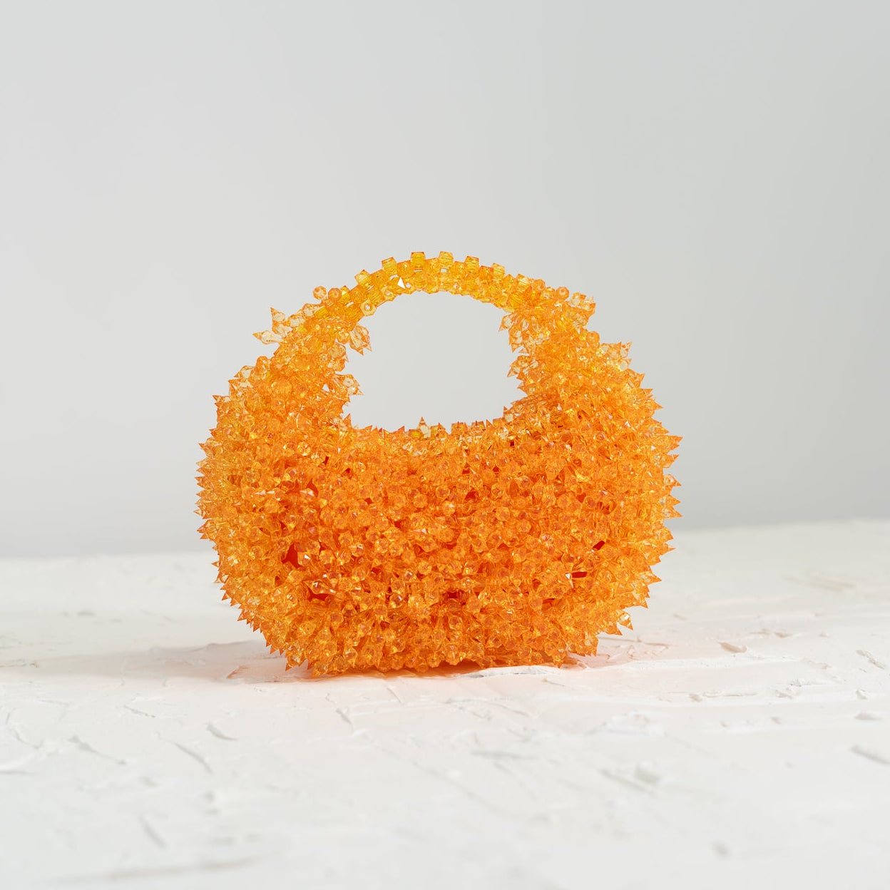Orange textured bag on a white surface with a light gray background