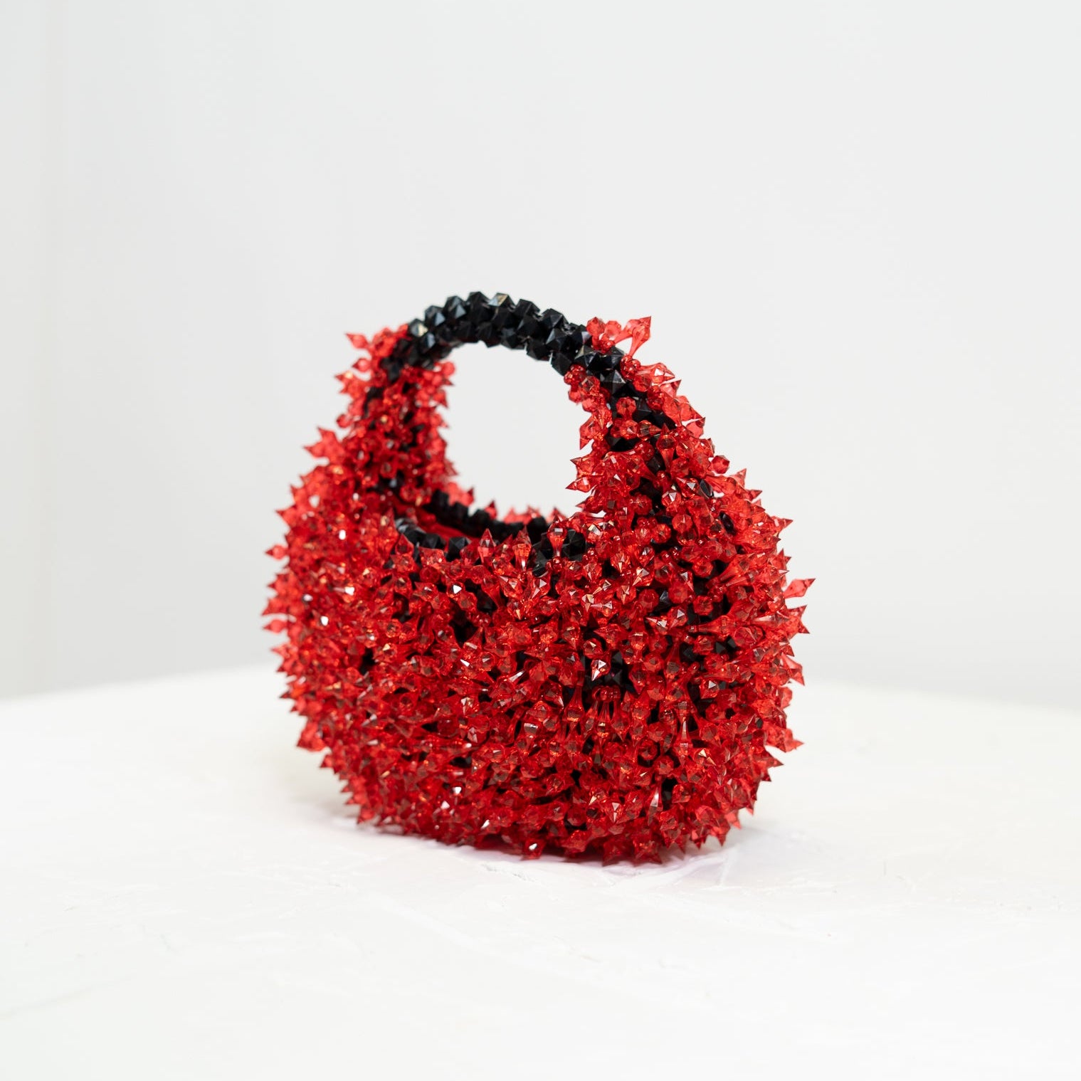 Red handbag with black handle on a white background