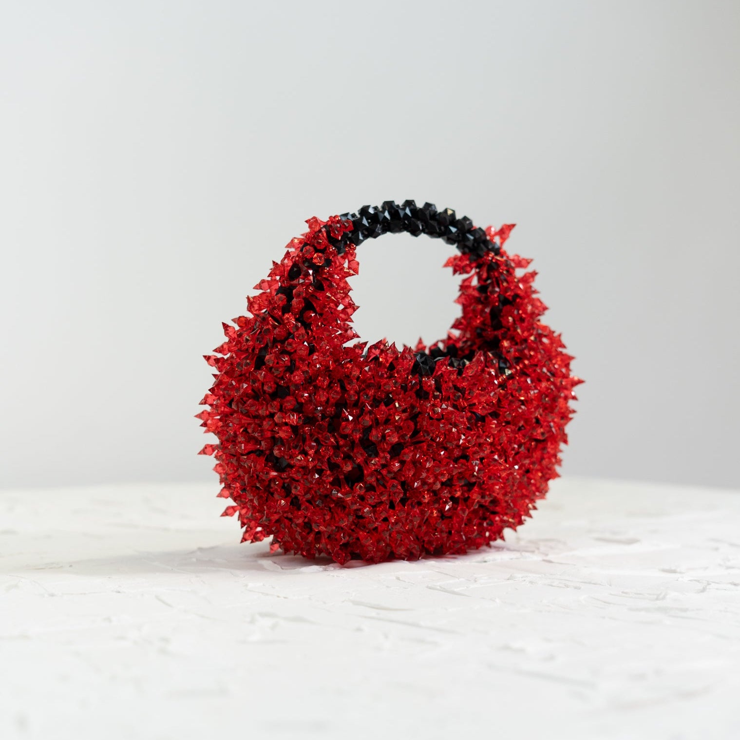 Red handbag with black handle on a white background