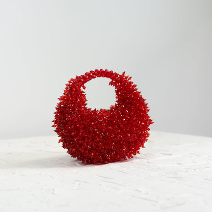 Red textured handbag on a white surface with a light gray background