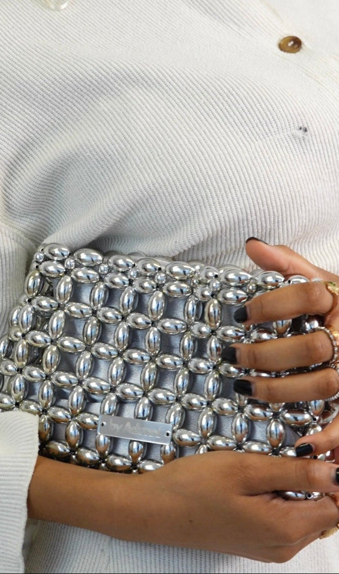 Woman holding a silver beaded clutch against a white background